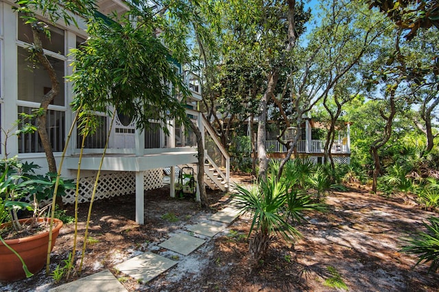 view of yard with a sunroom, a deck, and stairs