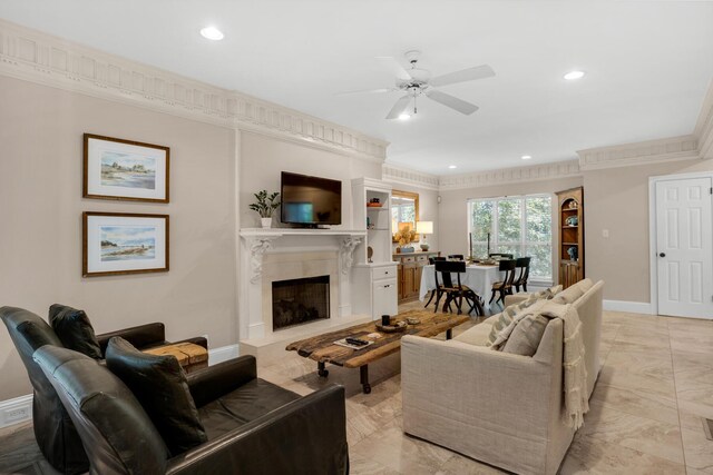 living room featuring a high end fireplace, crown molding, ceiling fan, and light tile patterned floors