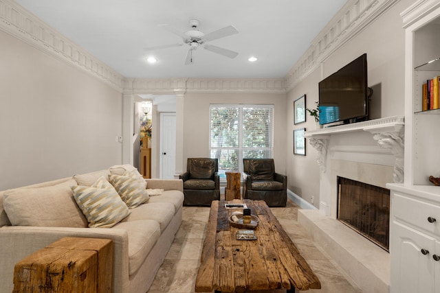 living room featuring a premium fireplace, crown molding, ceiling fan, and light tile patterned floors