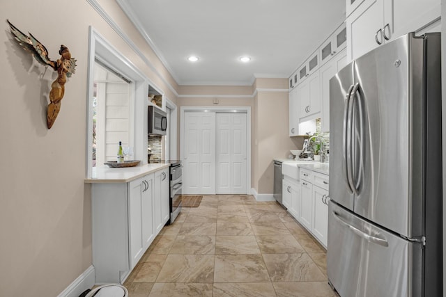 kitchen featuring appliances with stainless steel finishes, white cabinets, light countertops, and crown molding