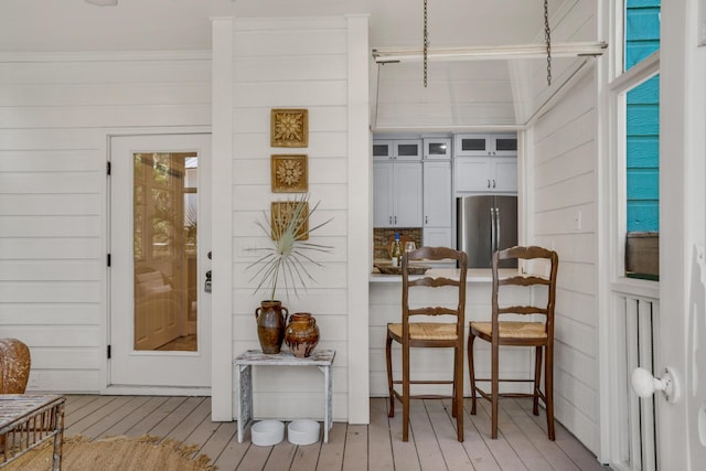 kitchen featuring a breakfast bar, white cabinets, light wood-style floors, freestanding refrigerator, and glass insert cabinets