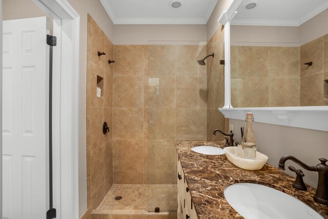 bathroom with crown molding, a tile shower, and double sink vanity