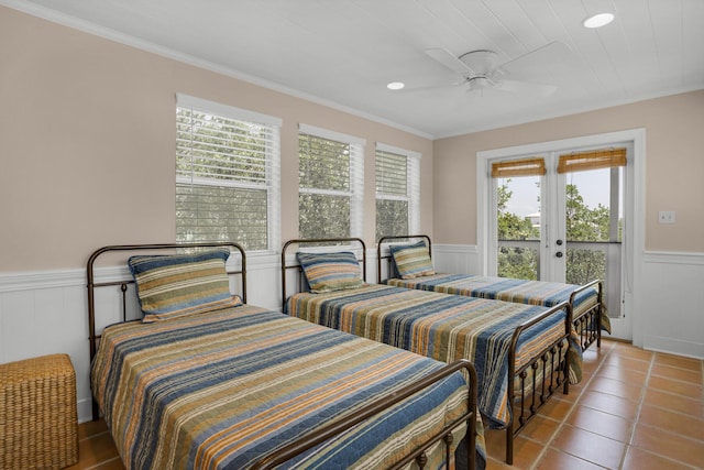 tiled bedroom with a wainscoted wall, ceiling fan, ornamental molding, access to exterior, and french doors