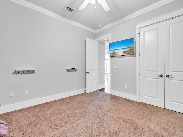 unfurnished bedroom with ceiling fan, ornamental molding, carpet, and a closet