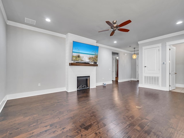 unfurnished living room with dark wood-type flooring, crown molding, a fireplace, and ceiling fan