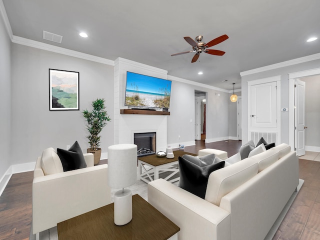 living room with crown molding, a large fireplace, wood-type flooring, and ceiling fan