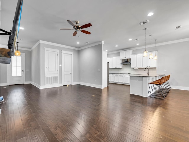 unfurnished living room with crown molding, ceiling fan, dark hardwood / wood-style floors, and sink