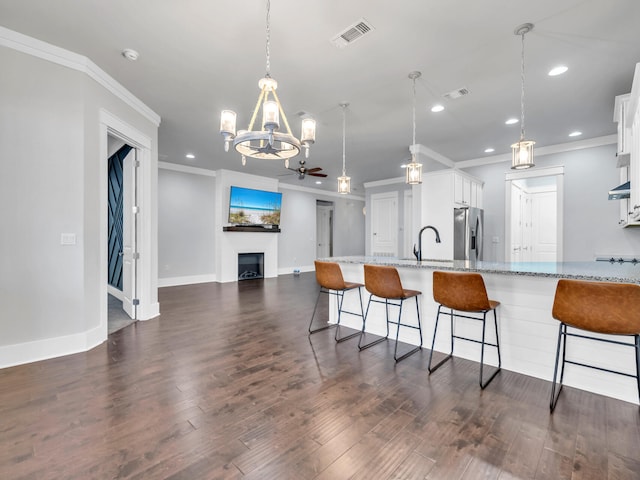 kitchen with pendant lighting, stainless steel fridge with ice dispenser, light stone countertops, and white cabinets