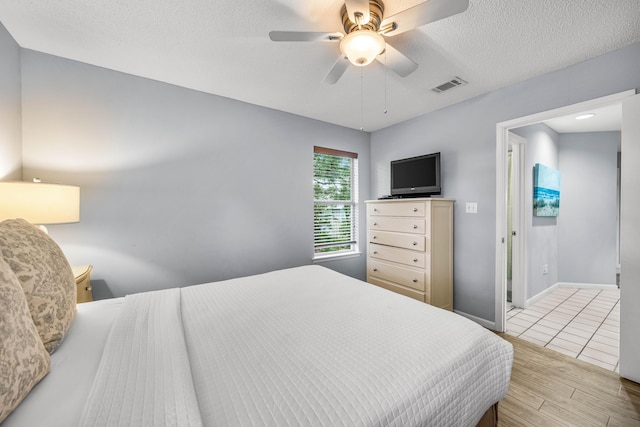 bedroom with ceiling fan, a textured ceiling, and light wood-type flooring