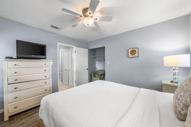 bedroom with ceiling fan, a closet, a textured ceiling, and light wood-type flooring