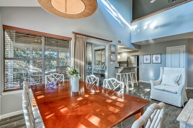 dining space featuring plenty of natural light, a towering ceiling, and dark hardwood / wood-style flooring