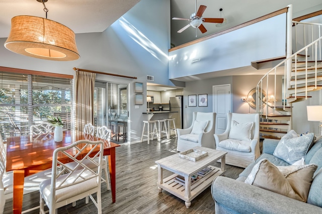 living room featuring wood-type flooring, a towering ceiling, and ceiling fan