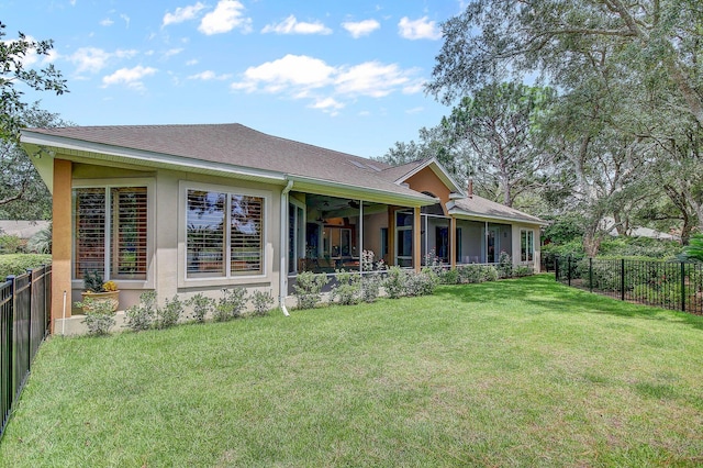 back of property with ceiling fan and a yard