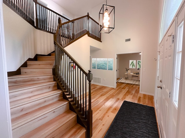 entrance foyer with a towering ceiling, light hardwood / wood-style flooring, and a notable chandelier