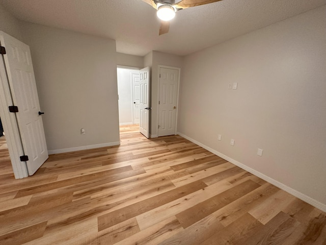 unfurnished bedroom featuring ceiling fan, a textured ceiling, and light wood-type flooring