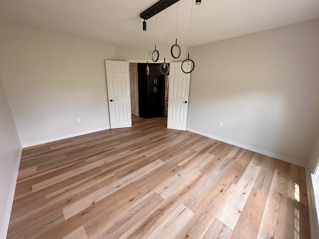 unfurnished dining area with a textured ceiling and light hardwood / wood-style floors