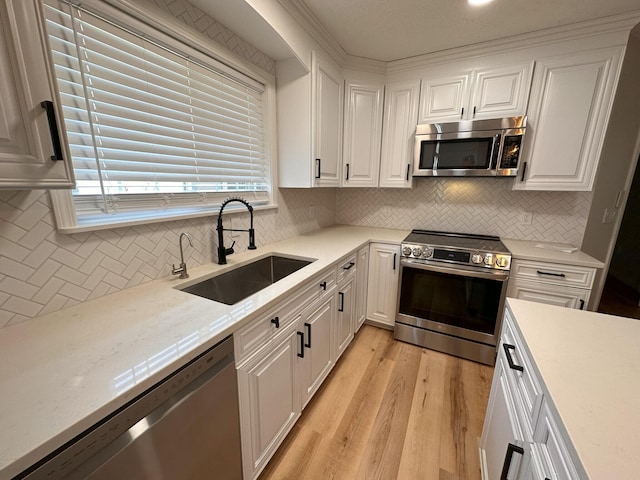 kitchen featuring sink, white cabinets, light hardwood / wood-style floors, stainless steel appliances, and light stone countertops