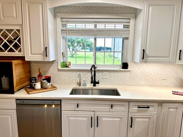 kitchen with backsplash, stainless steel dishwasher, sink, and white cabinets