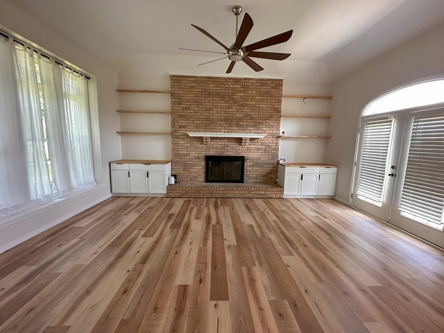 unfurnished living room featuring plenty of natural light, light hardwood / wood-style floors, and a brick fireplace