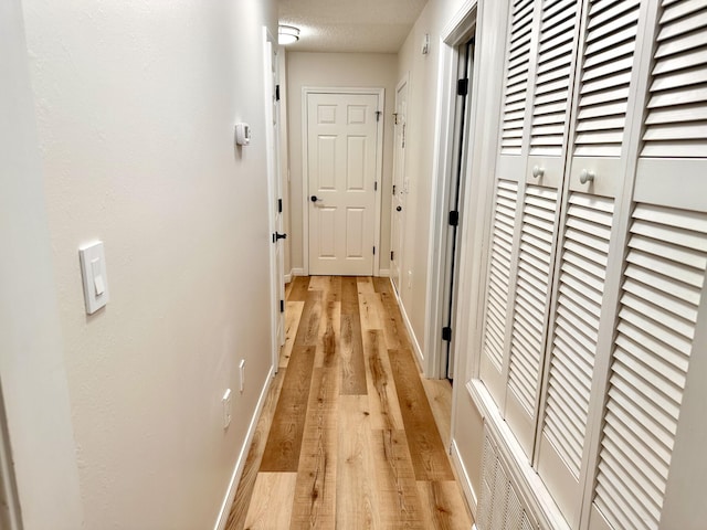 corridor featuring a textured ceiling and light wood-type flooring