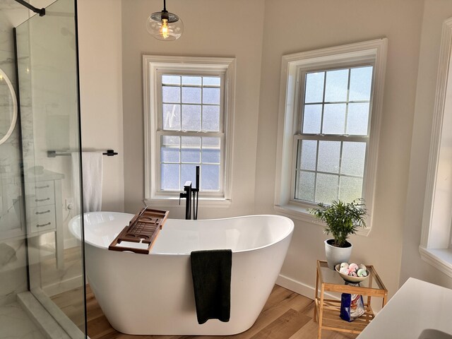 bathroom with wood-type flooring and shower with separate bathtub