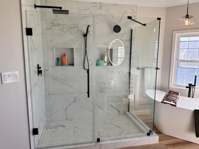 bathroom featuring wood-type flooring and shower with separate bathtub