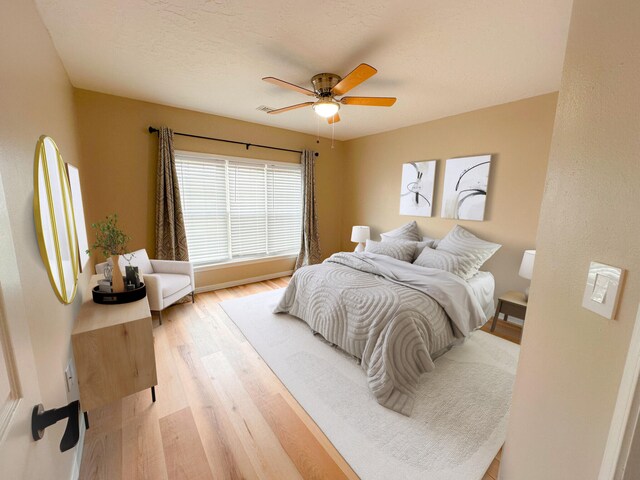 bedroom featuring ceiling fan, light hardwood / wood-style floors, and a textured ceiling