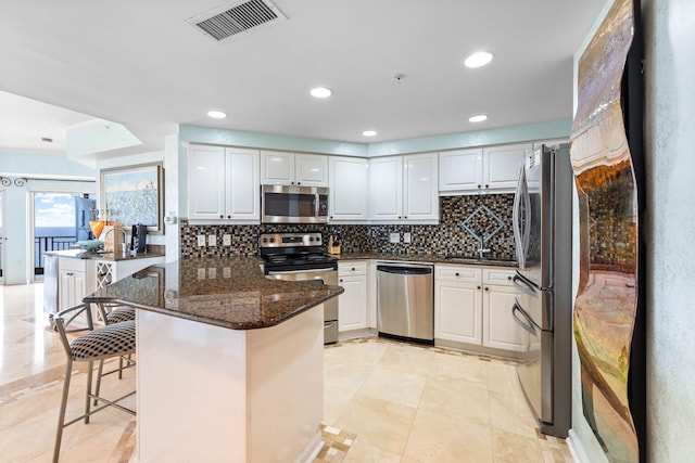 kitchen featuring white cabinetry, appliances with stainless steel finishes, a breakfast bar area, and kitchen peninsula