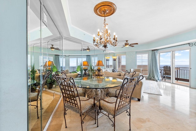 dining room with a raised ceiling and ceiling fan with notable chandelier