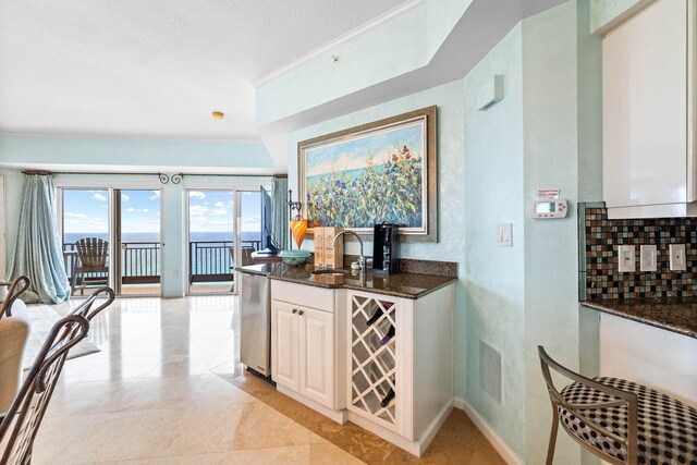 kitchen featuring dishwasher, white cabinetry, sink, backsplash, and dark stone counters