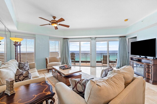 tiled living room with a tray ceiling and ceiling fan