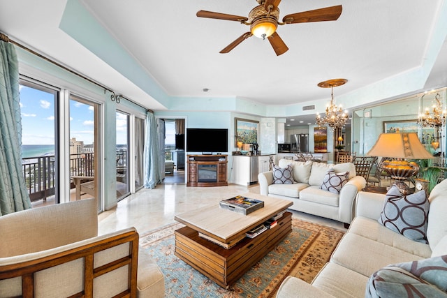 living room with a water view and ceiling fan with notable chandelier