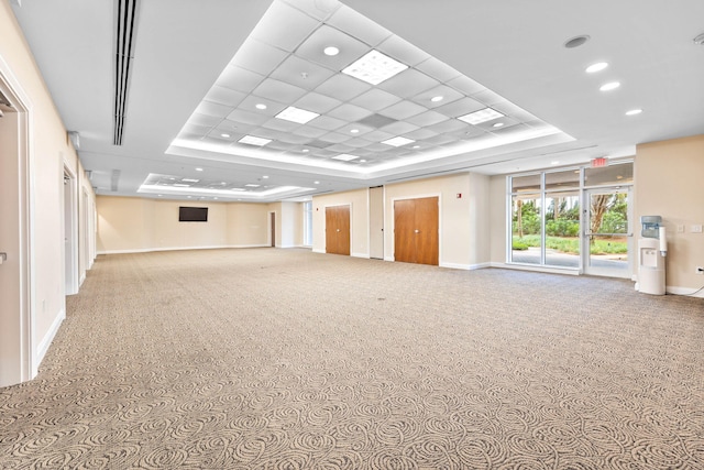 carpeted spare room featuring a raised ceiling