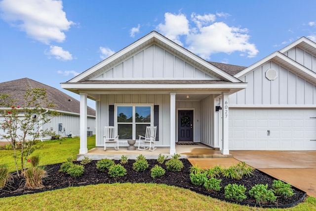 view of front of home featuring a garage, covered porch, and a front yard