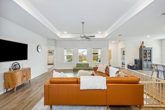 living room with ceiling fan, a tray ceiling, and light hardwood / wood-style flooring