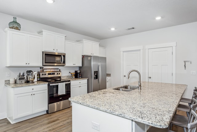 kitchen with an island with sink, appliances with stainless steel finishes, a kitchen bar, and sink