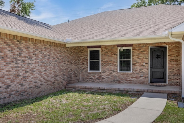 doorway to property featuring a patio and a lawn