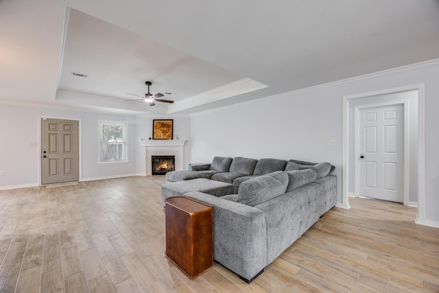 living room with ceiling fan, ornamental molding, and a tray ceiling