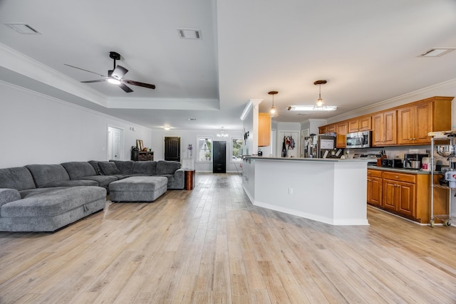 kitchen with light wood-type flooring, a center island, ceiling fan, a tray ceiling, and decorative light fixtures