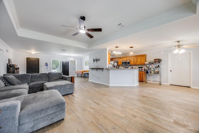 living room featuring ceiling fan, crown molding, light hardwood / wood-style flooring, and a raised ceiling