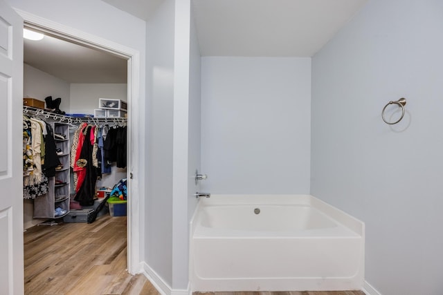 bathroom with a tub to relax in and hardwood / wood-style floors