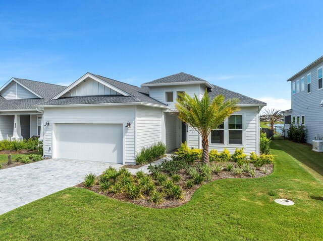 view of front of house with a garage, central AC, and a front lawn