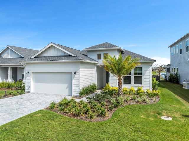 ranch-style house with a garage, a shingled roof, decorative driveway, board and batten siding, and a front yard