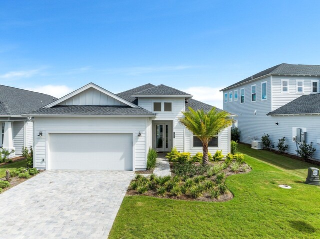 view of front facade with a garage, central air condition unit, and a front lawn