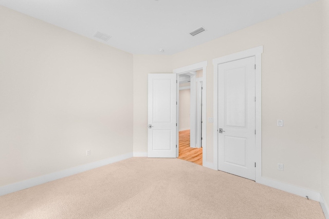 spare room with light carpet, visible vents, and baseboards