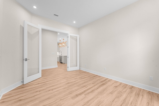 unfurnished room featuring light wood-style flooring, visible vents, baseboards, and french doors