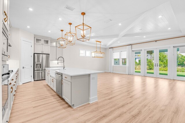 kitchen featuring open floor plan, decorative light fixtures, a kitchen island with sink, stainless steel appliances, and light countertops