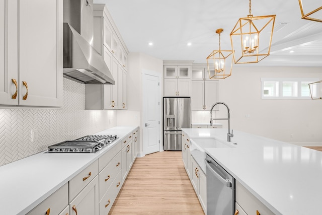 kitchen with decorative light fixtures, a sink, light countertops, appliances with stainless steel finishes, and glass insert cabinets