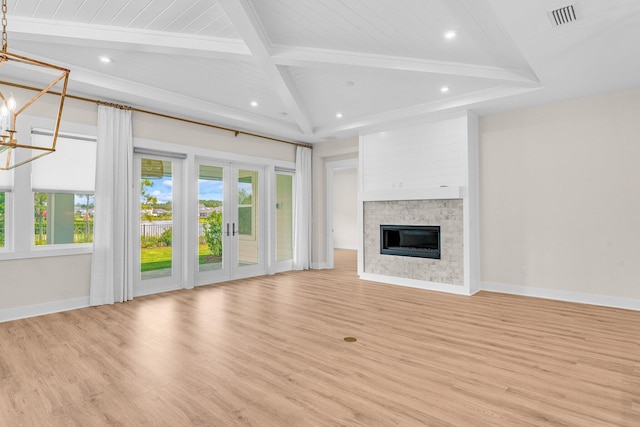 unfurnished living room featuring a chandelier, visible vents, beam ceiling, light wood finished floors, and a glass covered fireplace