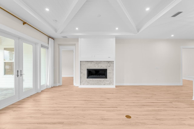 unfurnished living room with vaulted ceiling with beams, light wood-style flooring, visible vents, baseboards, and a glass covered fireplace